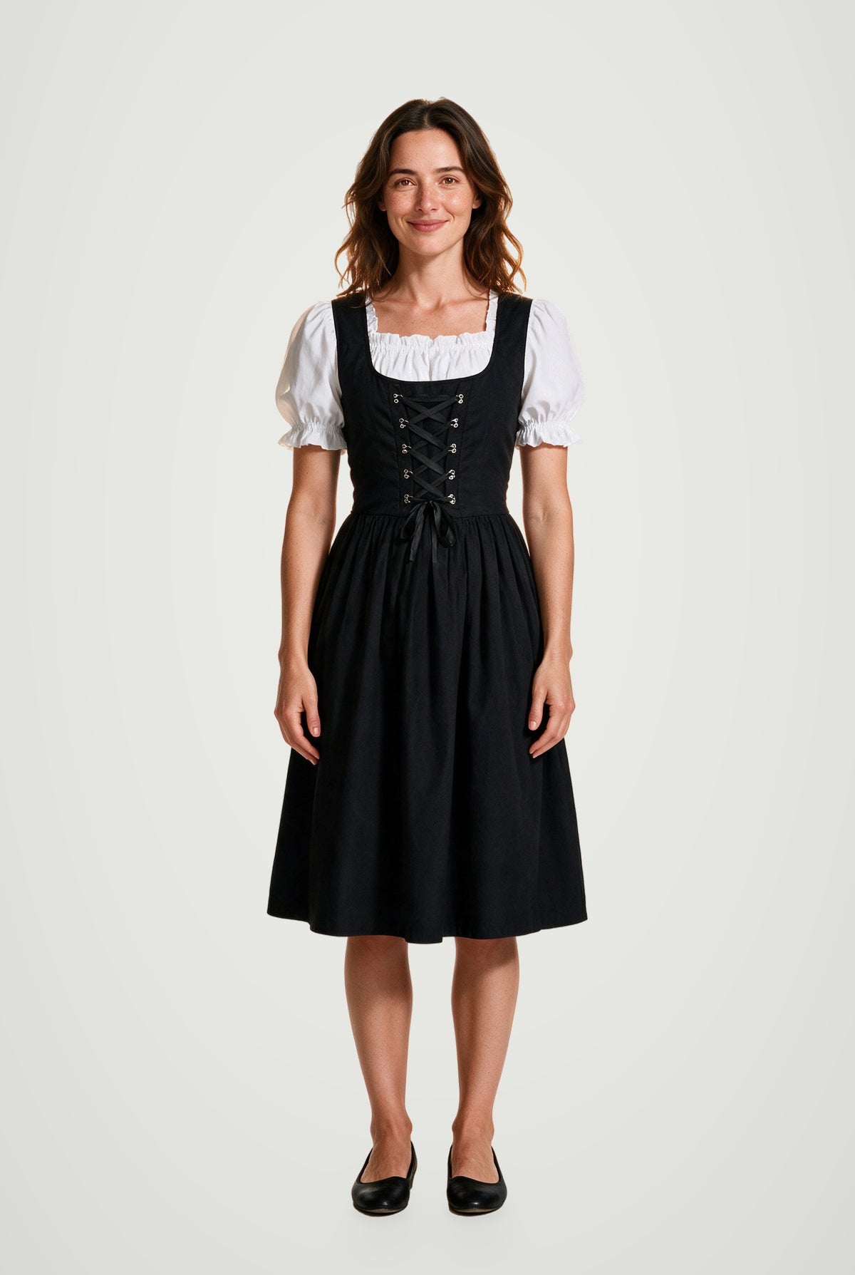 Woman wearing the Lorelei black dirndl dress with silver eyelet lacing and white puff-sleeve blouse, front view