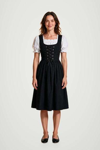 Woman wearing the Lorelei black dirndl dress with silver eyelet lacing and white puff-sleeve blouse, front view