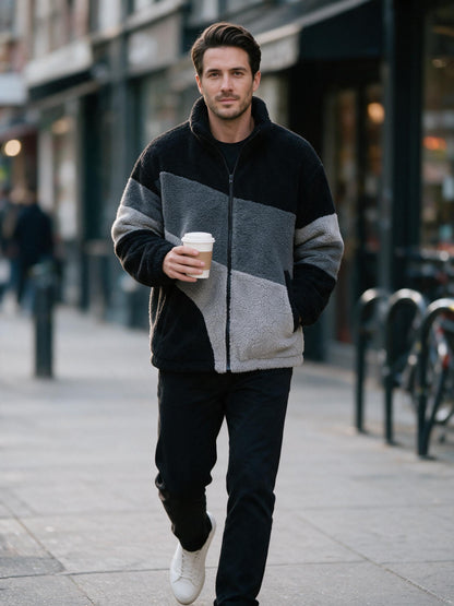 Man walking a city street with a coffee in the black and grey sherpa fleece jacket