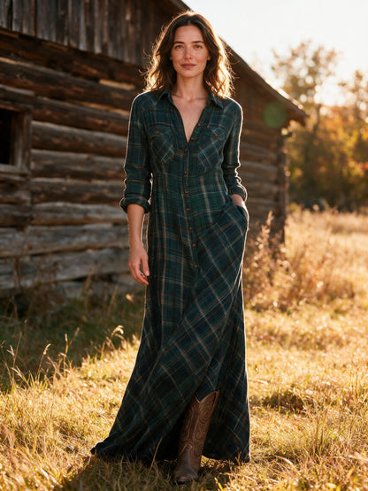 Woman wearing the green Tamsin plaid flannel maxi dress beside a timber barn in autumn