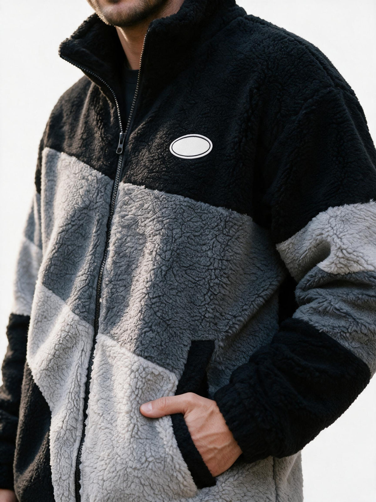 Close-up of the jacket's deep curly sherpa fleece pile, colour-block seam and front zip